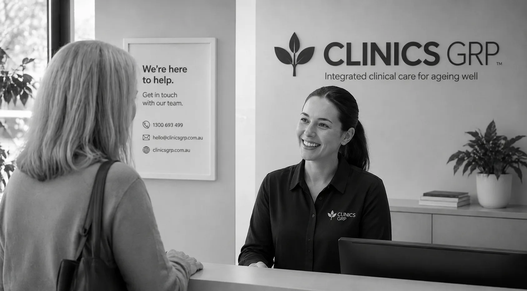 Clinics GRP receptionist speaking with a visitor at the intake desk.
