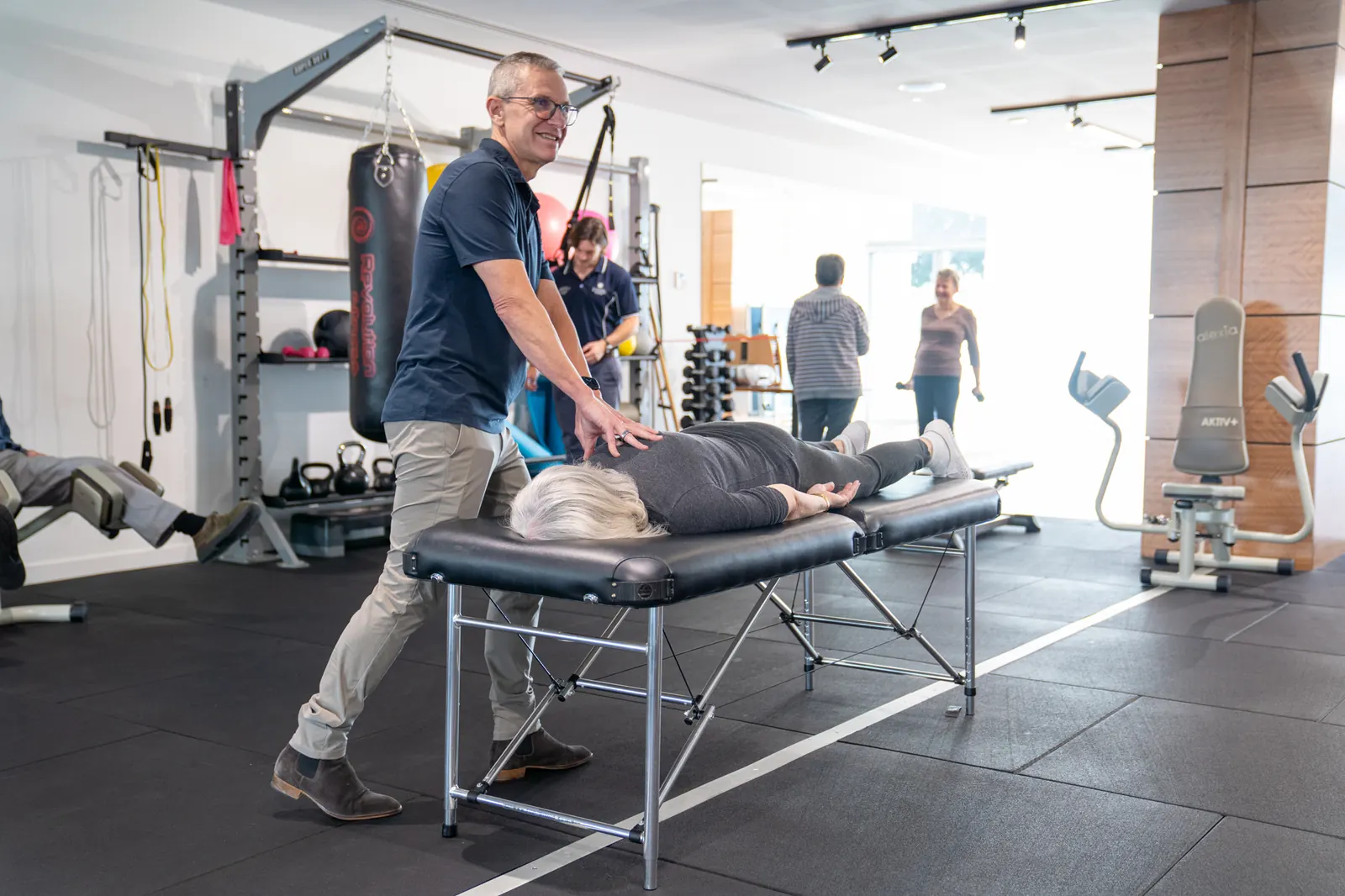 Clinician supporting an older adult in a rehabilitation and exercise setting.