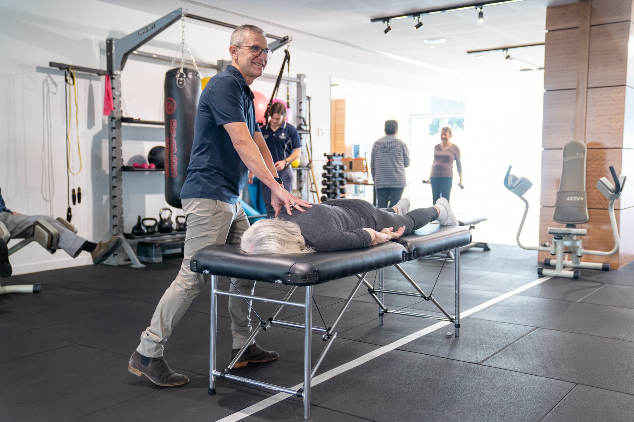 Clinician supporting an older adult in a rehabilitation and exercise setting.