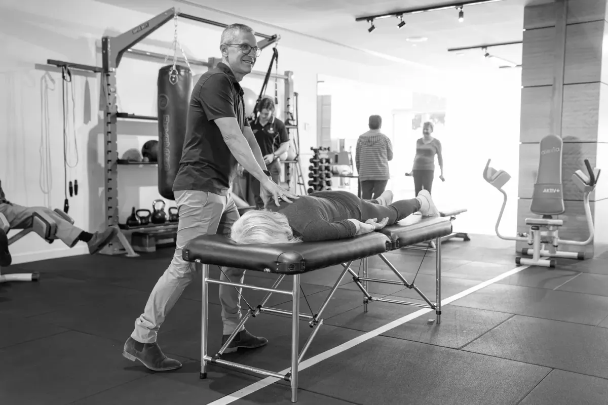 Clinician supporting an older adult in a rehabilitation and exercise setting.